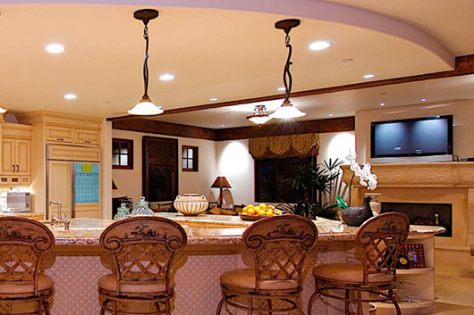 Large kitchen with curved island with stool seating, recessed lighting, and pendant lights over the island.