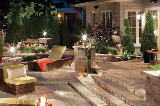 Large stone patio with furniture and patio lighting.