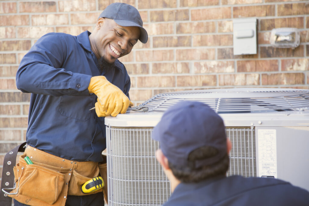 Two HVAC technicians servicing an air conditioner